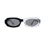 Oversized oval sunglasses with a black acetate front and temple arm, and a clear transparent acetate front, set against a light gray background.
